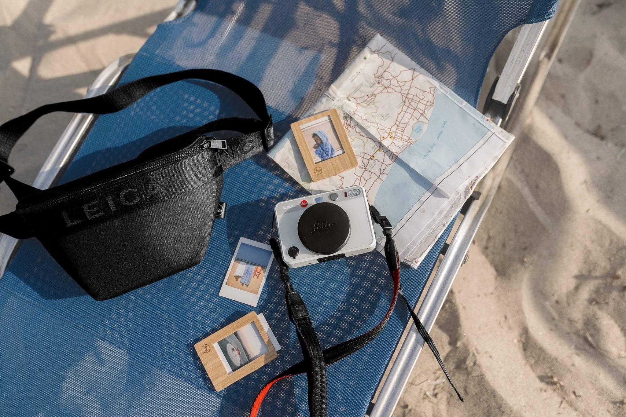 A picture of a camera on a beach blanket surround by a map and bag